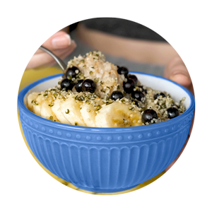 Shelled hemp seeds in a bowl of bananas and blueberries